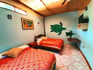 阿约拉港Alojamiento Sumak Kawsay的一间卧室设有两张床,墙上有一只海龟