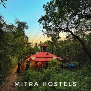 瓦加托Mitra Hostel Vagator的森林中一座红色屋顶的房子