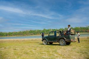 KawasotiGreen Chwadi Nature Retreat的停在河边田野上的绿色吉普车
