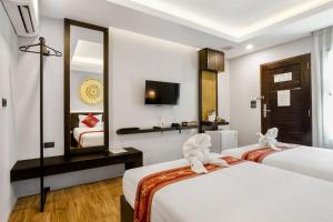 清迈Paraiso Hotel Chiangmai的酒店客房,设有两张床和镜子