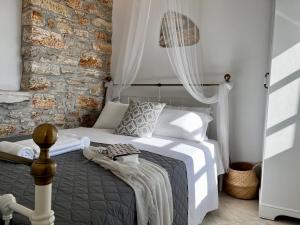 ApérathosPETRA HOME heritage and hospitality的一间卧室设有一张床和石墙