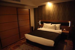 埃尔比勒埃尔比勒美尔奇酒店的一间卧室配有一张大床和木制床头板