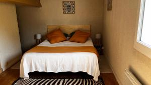 圣特罗让莱班Le Cocon Gite的一间小卧室,配有带橙色枕头的床