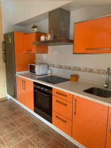 敦夫里亚Alojamientos A Pedra的厨房配有橙色橱柜、水槽和微波炉
