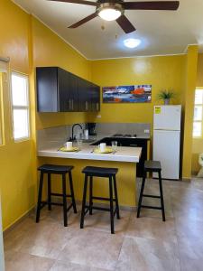 El YaquePosada Paraiso的厨房设有黄色的墙壁、柜台和凳子