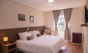 坎波斯杜若尔当Village de Charme的卧室设有一张白色大床和一扇窗户。
