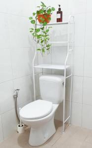 外南梦Snooze Ijen的浴室设有白色卫生间,架子上种植了植物