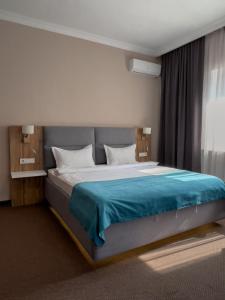 阿拉木图Keremet Hotel的一间卧室配有一张带蓝色毯子的大床