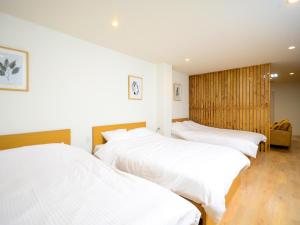 高松K's Hotel的配有白色床单的客房内的两张床