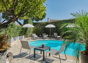 戛纳Hotel Le Suquet Cannes的一个带桌椅的庭院和一个游泳池