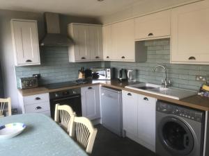布兰克斯特Lovely 3-Bed Cottage in Brancaster Staithe的厨房配有白色橱柜、水槽和洗碗机。