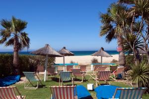 塔里法谭加纳简易别墅酒店的海滩上的一组椅子和遮阳伞