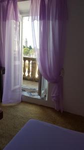 洛帕德Rooms Milena的客房设有带紫色窗帘的窗户。