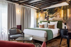 巴黎Hotel Louis II的卧室配有一张大床,墙上挂有绘画作品