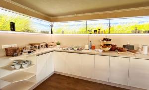普雷罗Pension Windrose的一间厨房,配有白色的橱柜和大窗户