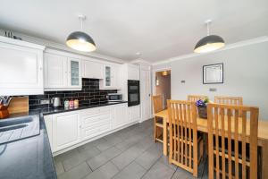 格拉斯哥Dalmarnock Stay的厨房配有白色橱柜和木桌