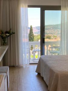 萨摩斯Ino Hotel & Suites的一间卧室设有一张床和一个享有美景的大窗户