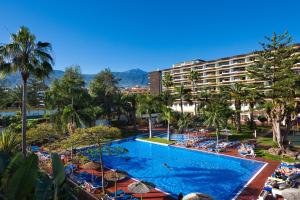 拉克鲁斯Complejo Blue Sea Puerto Resort compuesto por Hotel Canarife y Bonanza Palace的享有带椅子和棕榈树的度假村游泳池的景致