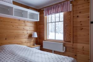 PelkosenniemiPyhä Saukonpiilo的卧室设有木墙、一张床和窗户