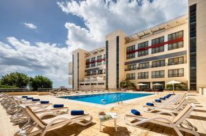 蓬塔德尔加达圣米格尔公园酒店的酒店游泳池设有躺椅,酒店大楼