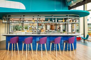 阿姆斯特丹YOTEL Amsterdam的一间酒吧,设有紫色和粉红色凳子