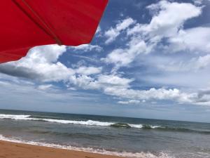 塞拉Casa beira mar Jacaraipe.的海滩上的红伞与海洋