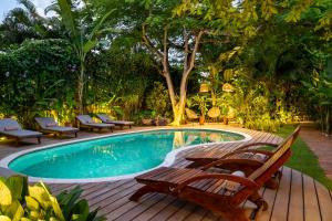 托兰克索Casa Das Águas Trancoso的一个带木甲板的游泳池,周围设有长椅