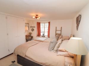 马姆斯伯里Hobbes Cottage的一间卧室配有一张带灯和窗户的床