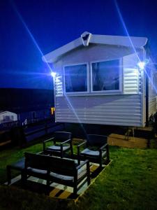 纽基4 Berth Couples and Family Caravan in Beautiful Newquay Bay Resort的一群长凳在一个小房子前面