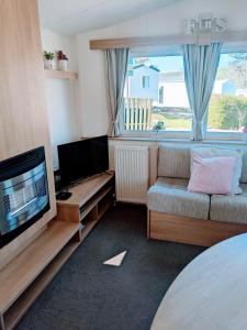 纽基4 Berth Couples and Family Caravan in Beautiful Newquay Bay Resort的带沙发和平面电视的客厅