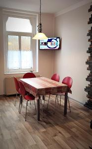 普劳恩Ferienwohnung am Birkenwäldchen的一间带木桌和红色椅子的用餐室