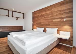 欣特察尔滕WaldFunkeln LODGE的卧室配有一张白色大床和木墙