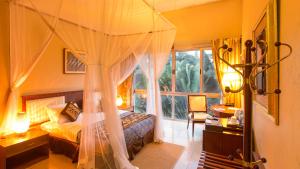 坎帕拉Humura Resorts的一间卧室配有一张天蓬床和窗户