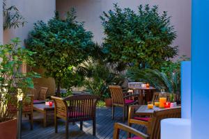 戛纳Citadines Croisette Cannes的庭院配有桌椅和树木