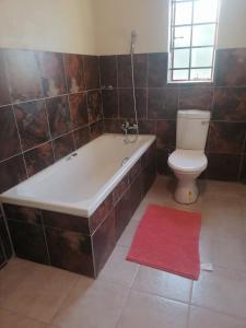 Ga-MathakoBophelo Guest House @ Pella的带浴缸和卫生间的浴室以及红色地毯。