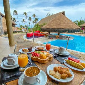 路易斯科雷亚Carnaubinha Praia Resort的一张带早餐食品的桌子和一个游泳池