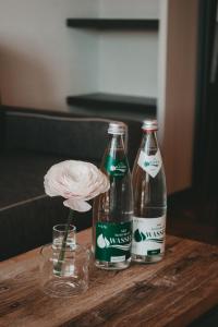 加姆利茨Winkel Art Hotel的木桌上放着两瓶可乐,一朵花