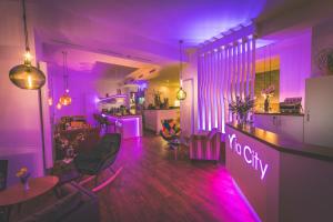莱比锡莱比锡米特城市酒店的紫色的客房设有1间带椅子和桌子的酒吧