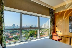 圣保罗Hilton Garden Inn Rebouças的卧室设有大窗户,享有城市美景。