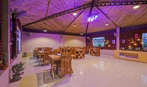 兰纳加Treebo Trend Kaira Resort With Pool View 5 Km From Jim Corbett Jungle Safari的餐厅设有木桌、椅子和紫色照明