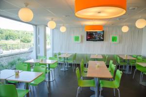 勒布朗-梅尼尔盖和纳巴黎勒布尔热机场宜必思快捷酒店的用餐室配有桌子和绿色椅子