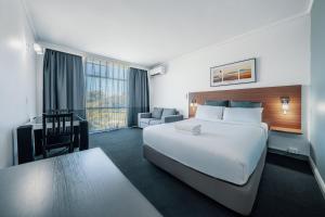 悉尼The Select Inn Ryde的酒店客房设有一张白色大床和一张书桌