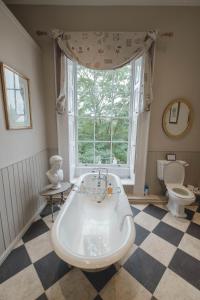德比Breedon Hall的带浴缸、卫生间和窗户的浴室