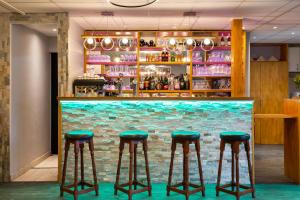 奥尔良Fasthotel Orleans Zénith的砖墙前的带绿色凳子的酒吧