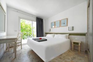 马斯帕洛马斯Vista Bonita - Gay and Lesbian Only Resort的一张白色的床,位于一个配有书桌和窗户的房间