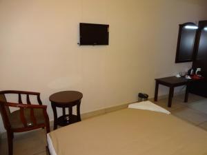 哥印拜陀天籁机场酒店的一间设有床铺和墙上电视的客房