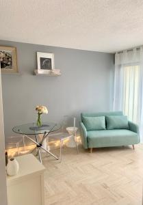 曼德琉-拉纳普勒Lovely Appartment Cannes Marina的客厅配有蓝色的沙发和玻璃桌