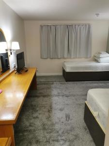 阿夫雷Thurrock Hotel M25 Services的客房设有两张床、一张桌子和一台电视。
