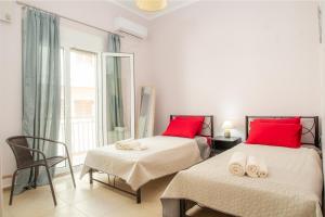 扎金索斯镇Agios Pavlos Corner Vacation House Zakinthos的一间卧室设有两张床、一把椅子和一个窗户。