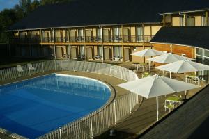 埃屈埃莫维尔阿多尼斯酒店的一个带遮阳伞和桌子的游泳池以及一座建筑